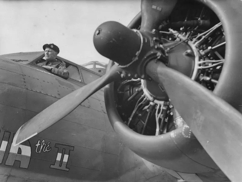 A Sergeant Major of the 55th Royal Armoured Corps in the cockpit of a B-17 Flying Fortress nicknamed "Marina the II" of the 381st Bomb Group during a visit to Ridgewell. Passed as censored 1 Sep 1943. Printed caption on reverse: 'British Tank Men Visit "Flying Corps". Men of the 55th[obscured] Royal Armour Corps, many of whom have fought in Libya with the 8th Army, were invited to an American aerodrome "somewhere in Britain" to see Flying Fortresses. Keystone Photo Shows:- The R.S.M. of the tank men looks